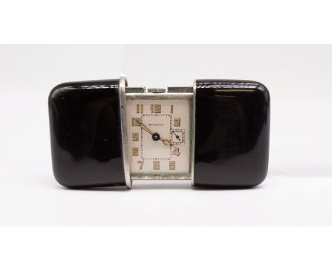 An Art Deco black enamel Movado travel clock, comprising a rectangular silvered dial with gilt painted Arabic markers, inner 