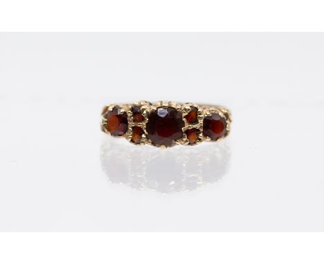 A garnet and 9ct gold ring, comprising three graduated round mixed cut garnets with smaller garnet accents, width approx 6mm,