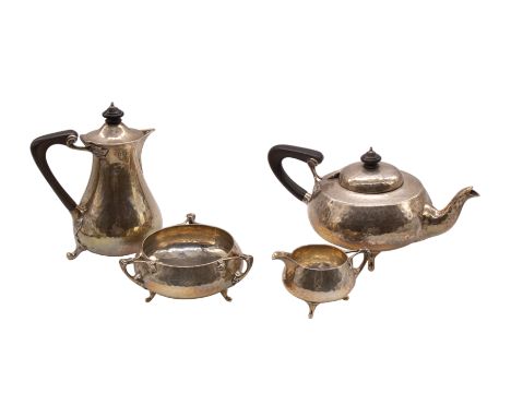 An Arts & Crafts four piece silver tea service comprising teapot, hot water jug, tri-handled sugar bowl and milk jug, squat h