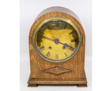 An early 20th Century oak cased 8 day mantle clock with brass face, Roman numerals in arched case.