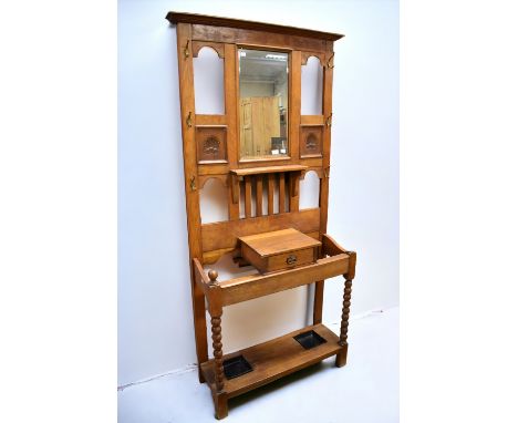 An Arts and Crafts style oak hall stand, having mirror to centre top, stick/umbrella stands to base, drip trays and single dr