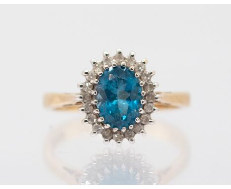 A 9ct gold blue topaz and diamond cluster ring, comprising an oval mixed cut topaz within a border of small diamonds, claw se