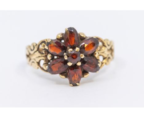 A garnet set 9ct gold cluster ring, comprising a flower head setting, of oval mixed cut stones, setting approx 12mm, fancy sh