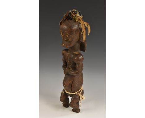 Tribal Art - an African fertility figure, seated on a stool, adorned with feathers and beadwork, 45cm high, probably Fang, Ce