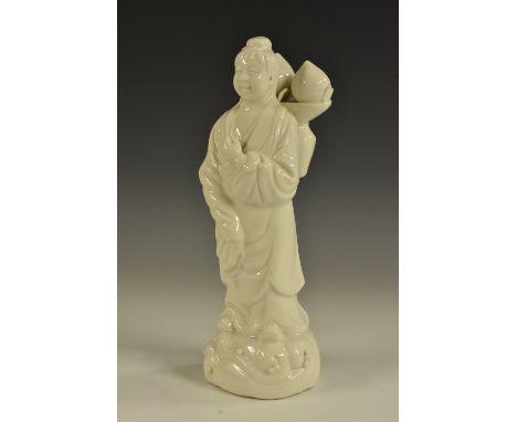 A Chinese Blanc de Chine Dehua porcelain figure, well-modelled as a winking sage, she stands in flowing robes, ripe peaches s