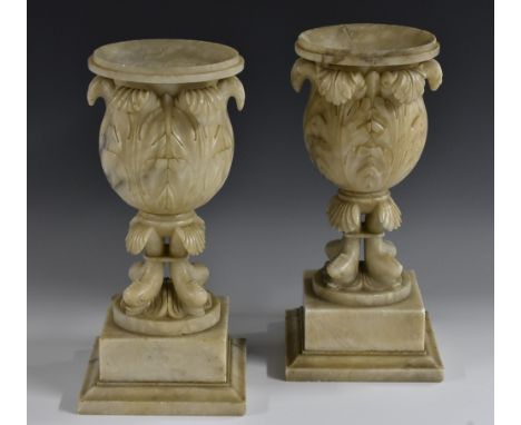 A pair of 19th century alabaster bell shaped mantel vases, boldly carved with scrolling acanthus, dolphin socles, square plin