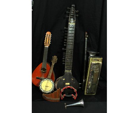 A group of stringed instruments including a sitar for restoration, banjolele etc, and a large novelty prop harmonica.