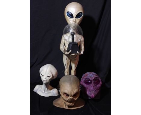 A freestanding figure of an alien holding lamp, height including base approx 100cm, a bust of an alien and two rubber heads (