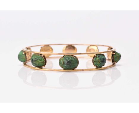 A yellow metal Scarab beetle set bangle, the iridescent Scarabs mounted to yellow metal openwork bangle, not stamped, inner d
