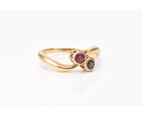 A French ruby and sapphire crossover ring, the two round mixed cut stones mounted in yellow metal, ring size L 1/2, weight ap