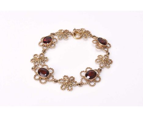 A 9ct gold garnet bracelet, designed as four oval mixed cut garnets milligrain set within a lobed rope border and intersperse