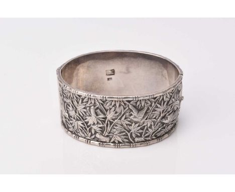 A Chinese silver bangle by Wang Hing, with chased bamboo and bird decoration, stamped 'Wang Hing' '90', inner diameter approx