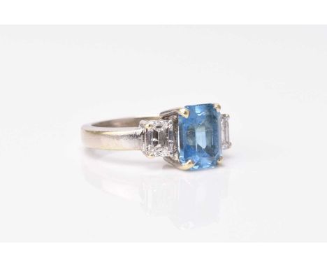 A 9ct white gold three stone blue topaz and diamond ring, designed as a central rectangular cut topaz flanked to each side by