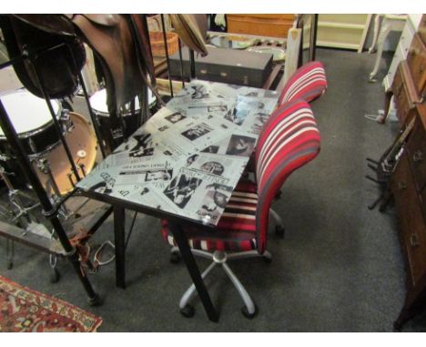 A modern metal desk with glass form top decorated in newspaper cutout design with three modern chairs 