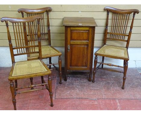 A MAHOGANY POT CUPBOARD and three cane seated bedroom chairs by Lamb of Manchester, the chairs with stick backs and delicate 