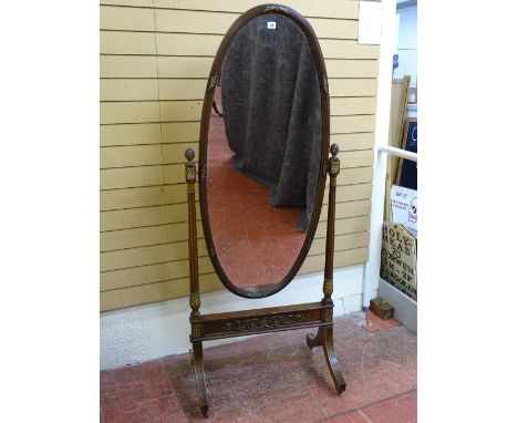 A REGENCY STYLE MAHOGANY OVAL DRESSING MIRROR with reeded and gilt highlighted decoration and cone finial caps, 176 cms high 