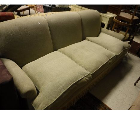 A modern pale green upholstered three seat scroll arm sofa with tassled base in the Howard style