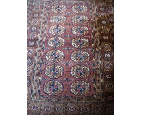 A Tekke Bokhara rug, the central panel set with repeating elephant foot medallions on an aubergine ground within a stepped au