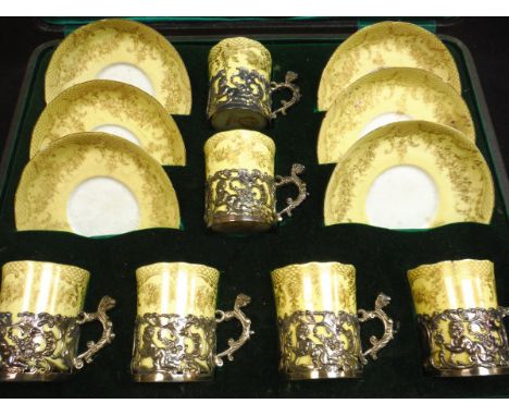 A cased set of six silver mounted Staffordshire coffee cans and saucers, the mounts set with C scroll and cherub decoration (