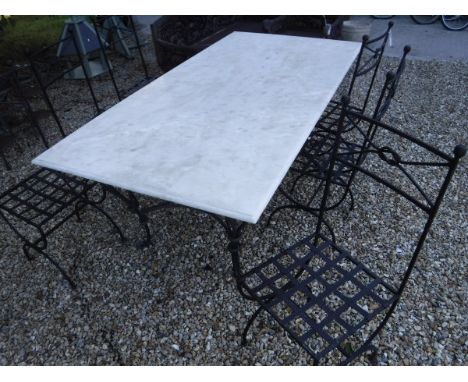A wrought iron and marble top garden table and set of six painted metal chairs with lattice seats and knop decoration to back