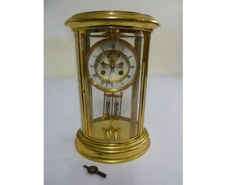 Gilt metal and four glass oval mantle clock, two train movement, striking to include mercury pendulum and key