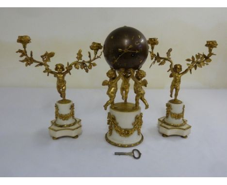 A late 19th century French mantle clock. The globular clock supported by putti on white marble cylindrical base with two matc