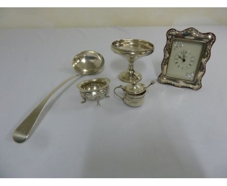 A quantity of silver to include a ladle, a bonbon dish, condiments and a silver mounted desk clock