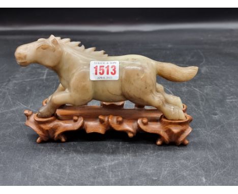 A Chinese jade horse,&nbsp;19cm long, on fitted hardwood stand.&nbsp; 