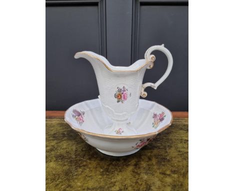 A 19th century porcelain ewer and basin, painted with flowers and with basketweave decoration, the jug 22cm high, (repairs to