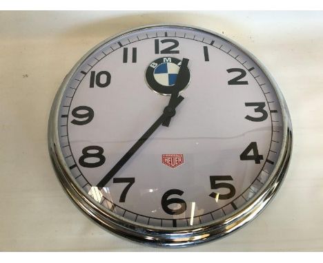 A decorative chrome framed circular wall clock with BMW decals.