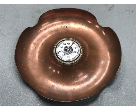 An AT Speedometer Co. Ltd. copper ashtray by F.W. Miller & Co. with central enamel speedometer disc.