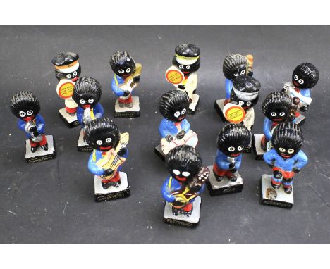 A group of Robertson's painted ceramic and plastic golly figures. One a footballer, three as lollypop people, the rest musici