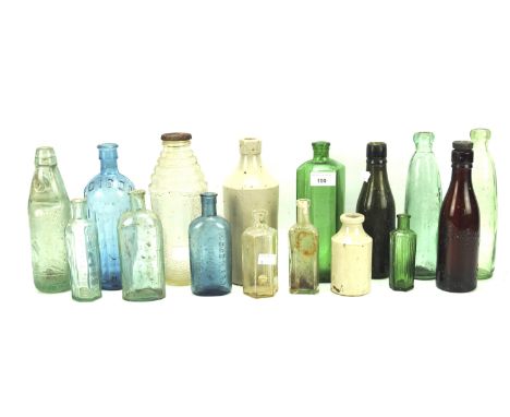 An assortment of vintage glass storage bottles and two ceramic examples. In blue, green brown and colourless glass, one marke