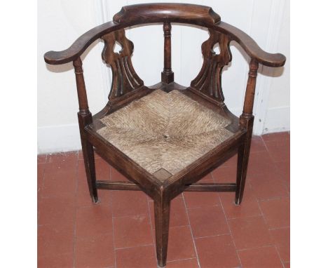 A George II oak corner elbow chair, the inverted vasular splat pierced with ?spades?, drop-in rush seat, tapered square legs,