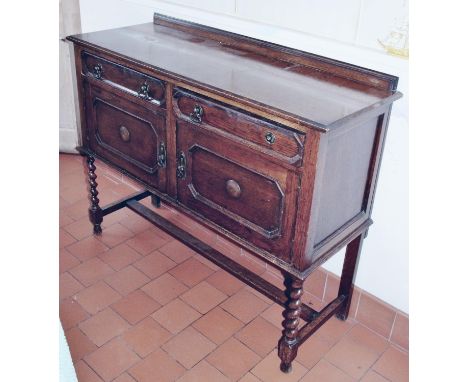 A Jacobean Revival oak sideboard, slightly over-sailing top above a pair of drawers and cupboards, applied with mouldings, sp