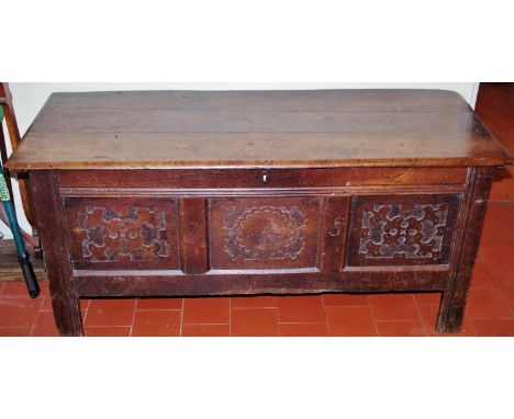 A late 17th/early 18th century oak blanket box, the top of plank construction above a three-panel front, carved with stylised