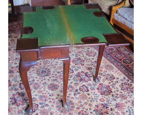 A George II mahogany card table, the rectangular top with block angles, folding enclosing candle stands to angles, above a de