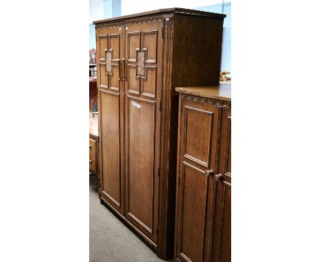 A 20th century carved oak three-part bedroom suite designed by Herbert Davis Richter comprising: panel fronted double wardrob