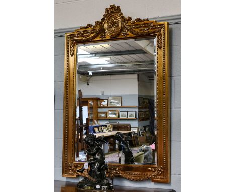 A reproduction gilt mirror, ornamented with tied ribbon and husk swags and with beaded border , 85cm by 125cm