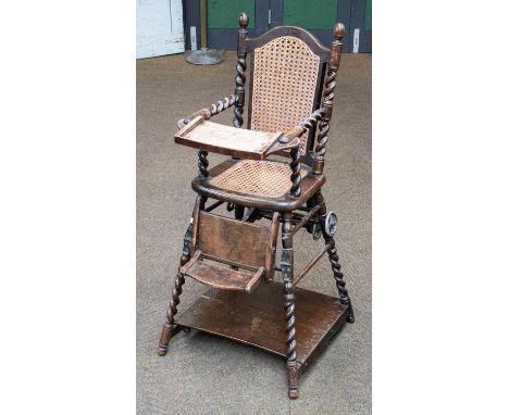 A 1920s oak metamorphic high chair, with cane back and seat and barley twist supports, bearing label Millson's Baby Cars &amp