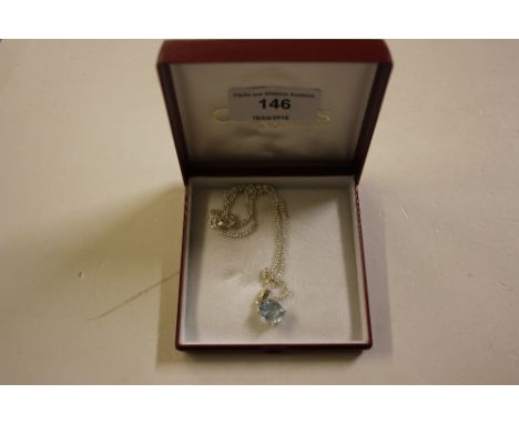 A silver chain hung with an aqua marine coloured pendant 