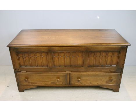 Ercol elm entertainment cabinet having panelled fall front top with twin drawers beneath, each with turned knob handles, rais