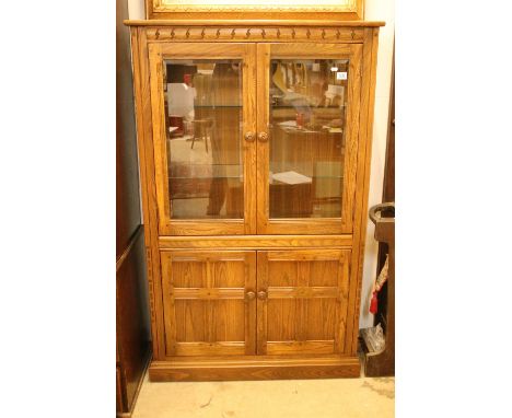 Ercol elm display cabinet having twin glazed doors with glass shelves within to top, with twin door cupboard to base. Measure