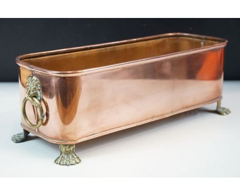 Copper rectangular planter with rolled rim, brass lion mask drop ring handles and four brass lion paw feet, 38cm long x 14cm 