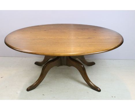 Ercol elm low coffee table having an oval top raised on a central column with four splayed legs. Legs with inlaid Ercol maker