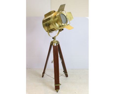 Floor standing standard lamp in the form of a vintage brass film or theatre spotlight held on an extending brass and mahogany