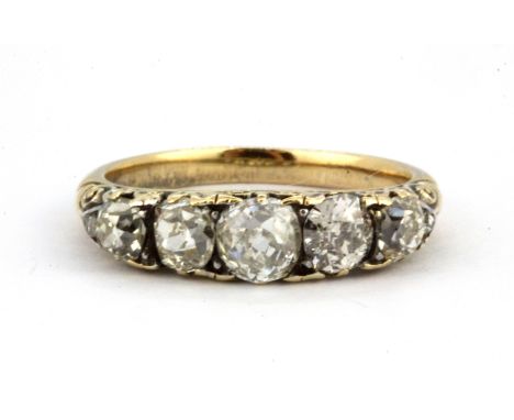 A yellow metal (tested 18ct gold) ring set with five graduated old cut diamonds, (L).