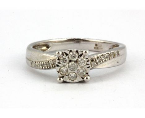A 9ct white gold diamond set cluster ring with diamond set shoulders, (L).