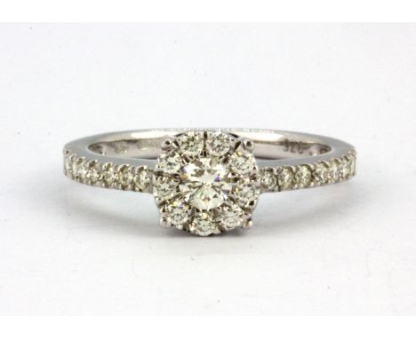 A 9ct white gold diamond set cluster ring with diamond set shoulders, (M.5).