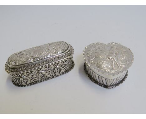 Two silver embossed trinket boxes, one of heart form with figural scene, the other with scrolled foliate design, vacant carto